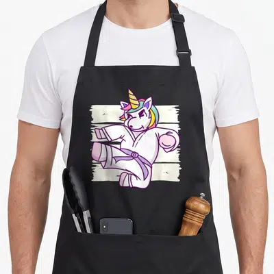 Tablier de cuisine noir avec une licorne en kimono blanc effectuant un coup de pied martial coloré.