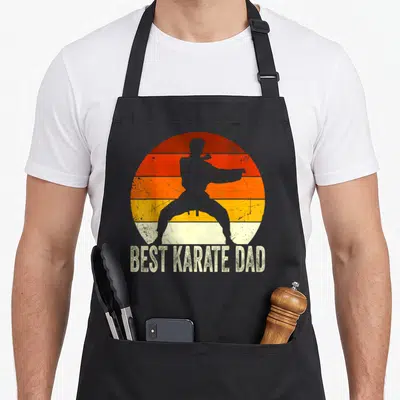 Tablier de cuisine noir avec silhouette karatéka et texte Best Karate Dad sur fond orange rétro.
