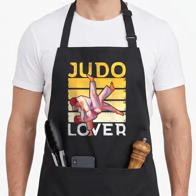 Tablier de cuisine noir avec illustration vintage de deux judokas et le texte « Judo Passionné » imprimé en orange et blanc.