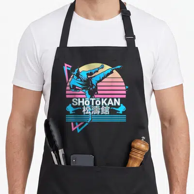 Tablier de cuisine noir avec illustration rétro d'un pratiquant de Shotokan Karaté Japonais et texte blanc.