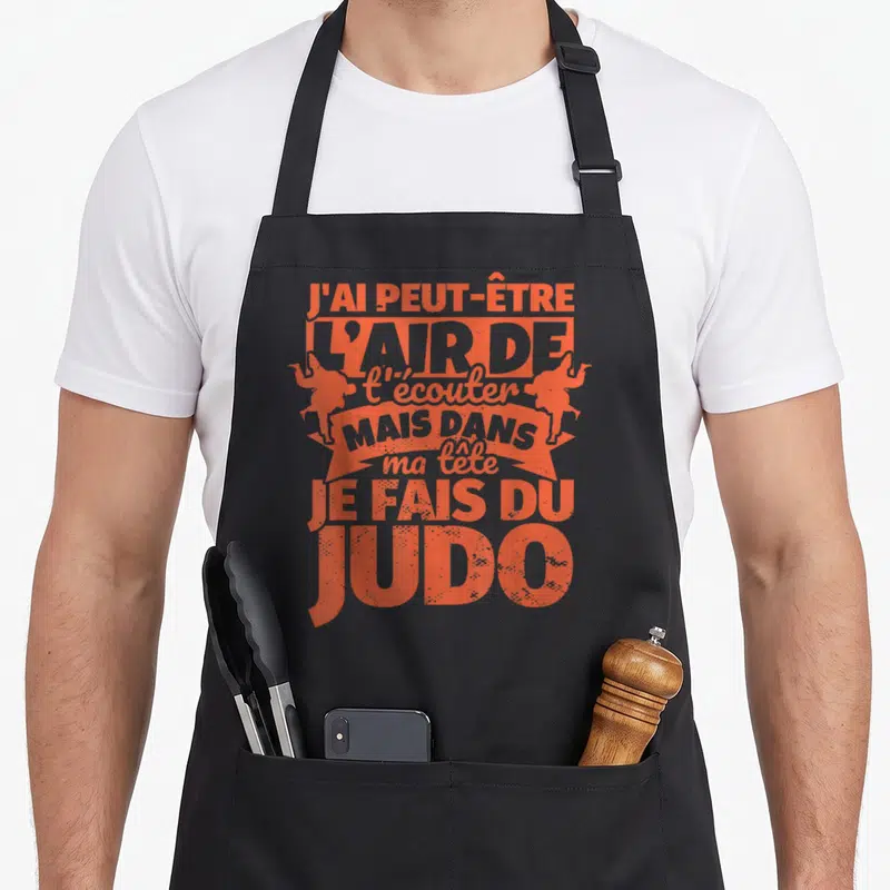 Tablier de cuisine noir avec typographie orange et silhouettes de judokas en position de combat.