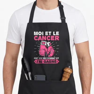 Tablier de cuisine noir avec gants de boxe roses et texte sur la victoire du cancer du sein.