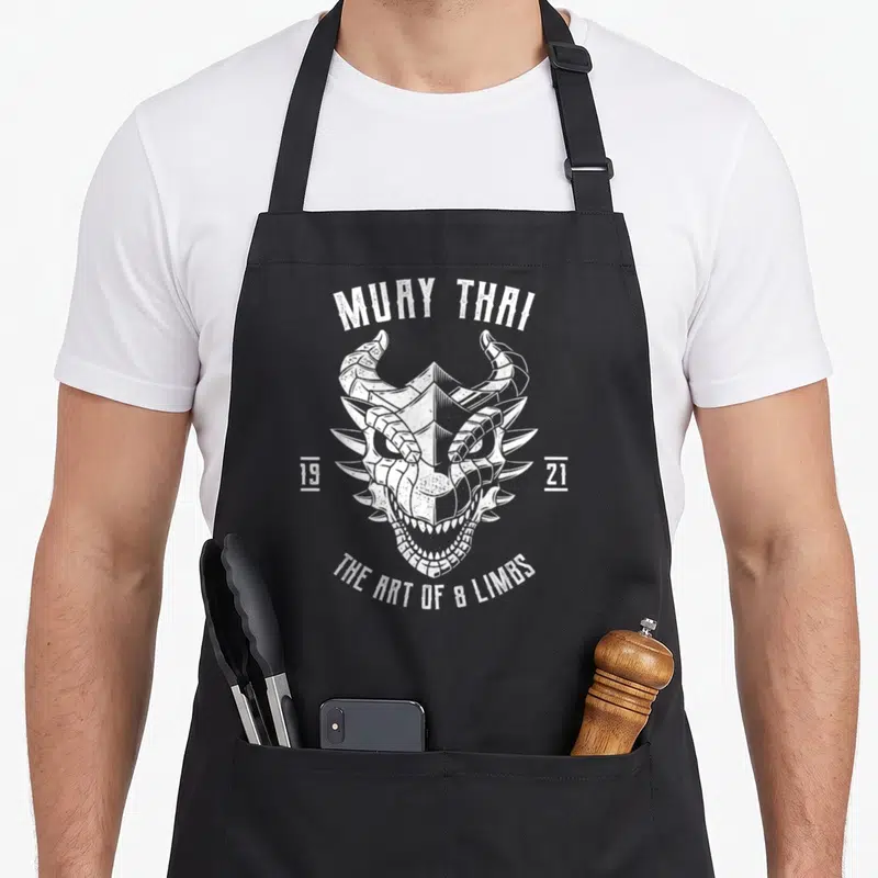 Tablier de cuisine noir avec tête de dragon stylisée blanche et texte Muay Thai 1921.