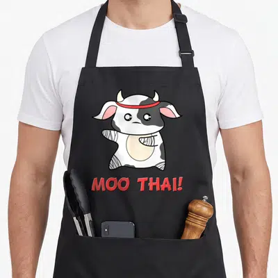 Tablier de cuisine noir avec une vache muay thai bandée et linscription Moo Thai en rouge.