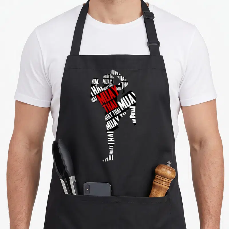 Tablier de cuisine noir avec silhouette de combattant Muay Thai composée de texte typographique noir blanc et rouge.