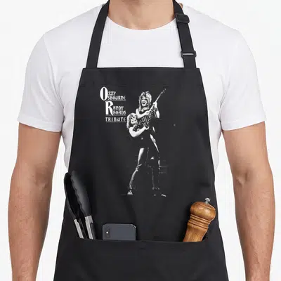 Tablier de cuisine noir avec illustration monochrome d'un guitariste et du texte Ozzy Osbourne Randy Rhoads Tribute en blanc.
