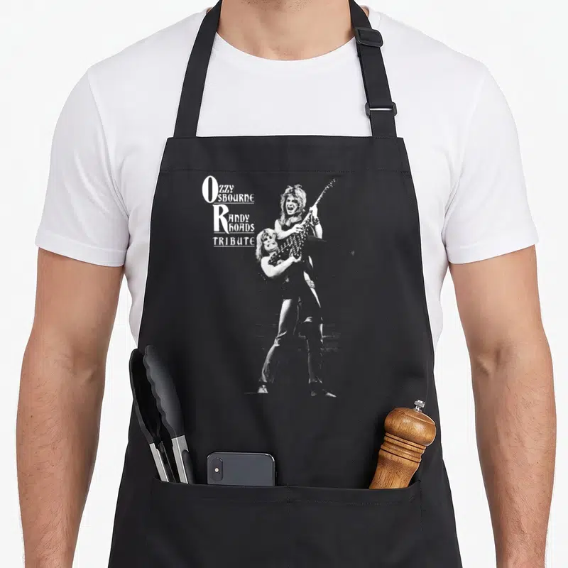 Tablier de cuisine noir avec illustration monochrome d'un guitariste et du texte Ozzy Osbourne Randy Rhoads Tribute en blanc.