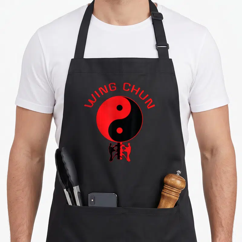 Tablier de cuisine noir avec un grand Yin Yang rouge et noir et deux silhouettes pratiquant le Wing Chun en dessous.