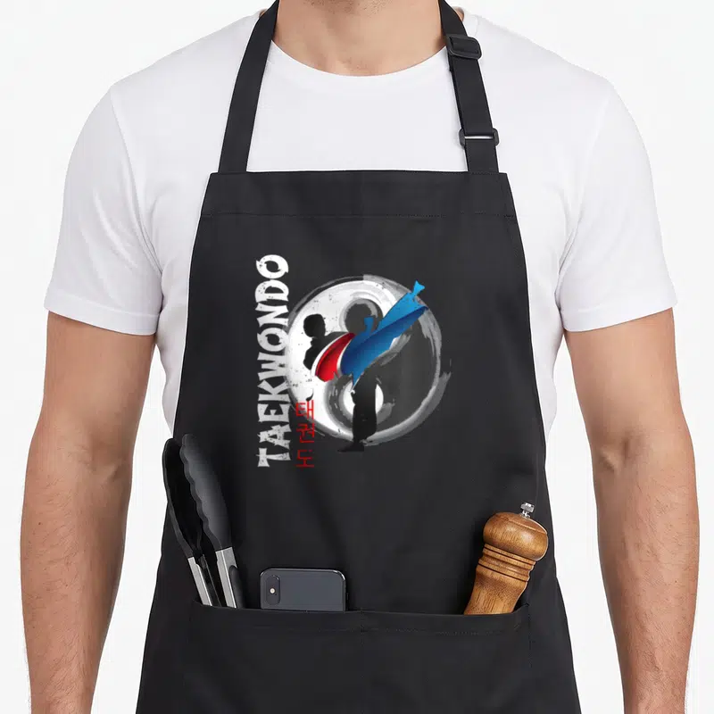 Tablier de cuisine noir avec silhouette de taekwondo et symbole Ying Yang rouge et bleu.