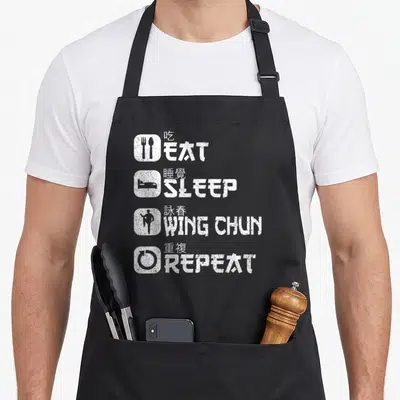 Tablier de cuisine noir avec inscription blanche EAT SLEEP WING CHUN REPEAT et symboles associés.
