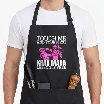Tablier de cuisine noir avec illustration rose d'un coup de pied et texte blanc Touch Me And Your First Krav Maga Lesson Is Free.