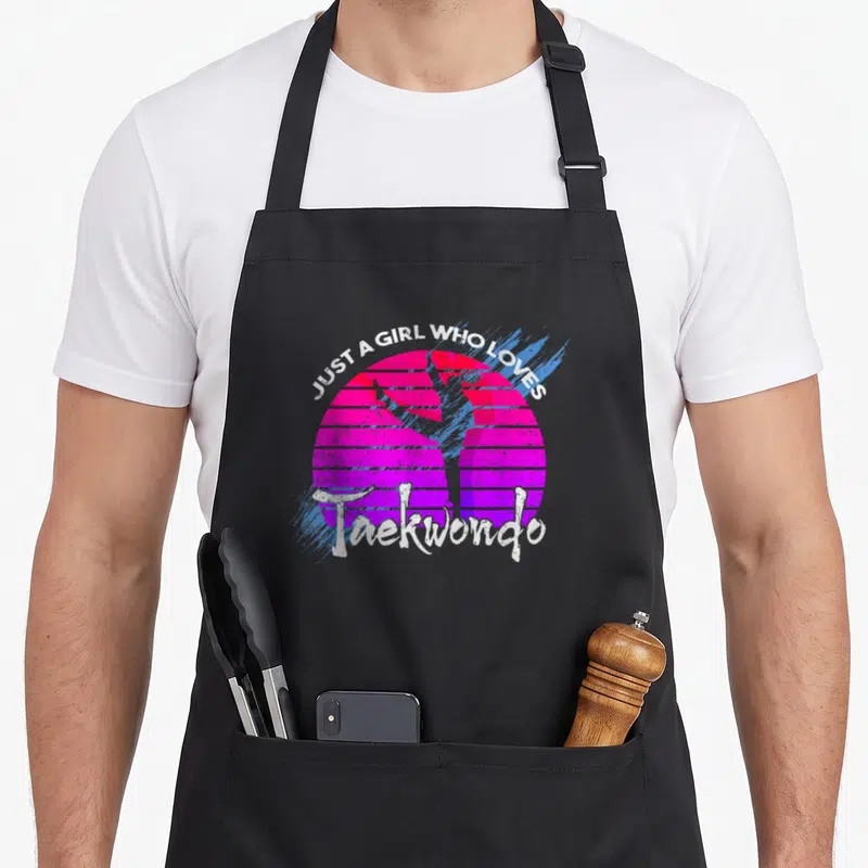 Tablier de cuisine noir avec silhouette de Taekwondo sur fond rose et texte blanc vintage.