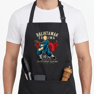 Tablier de cuisine noir avec illustration d'un combattant de Balintawak Escrima tenant des bâtons et un parasol rouge.