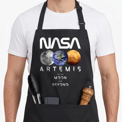 Tablier de cuisine noir avec logo NASA Artemis et trois planètes Lune Terre Mars alignées horizontalement.
