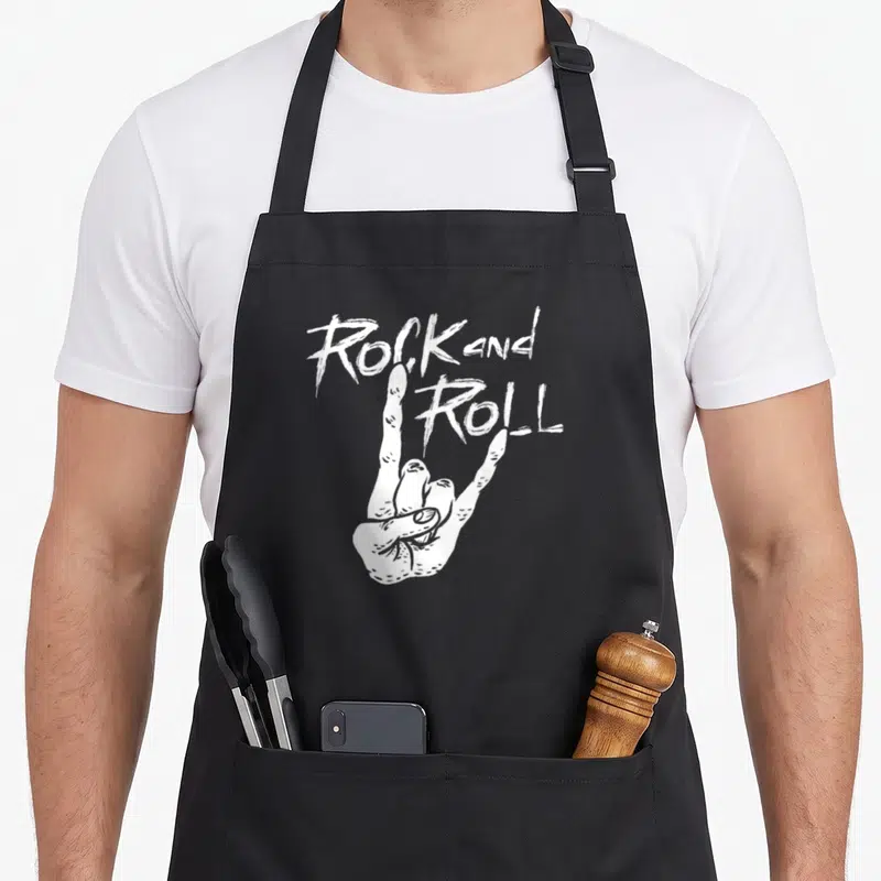 Tablier de cuisine noir avec main blanche formant les cornes du diable et texte Rock and Roll au-dessus.