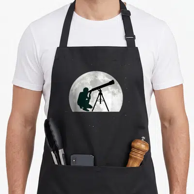 Tablier de cuisine noir avec silhouette observant la Lune via un télescope sur fond d'étoiles