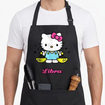 Tablier de cuisine noir avec Hello Kitty tenant des balances jaunes et le mot Libra en rose.