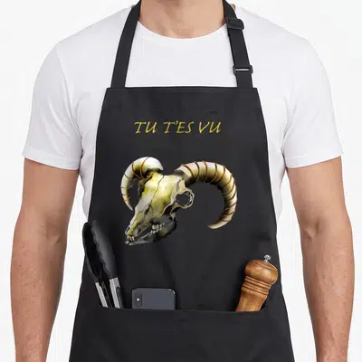 Tablier de cuisine noir avec une illustration de crâne de bélier et le texte Tu t'es vu en lettres dorées.