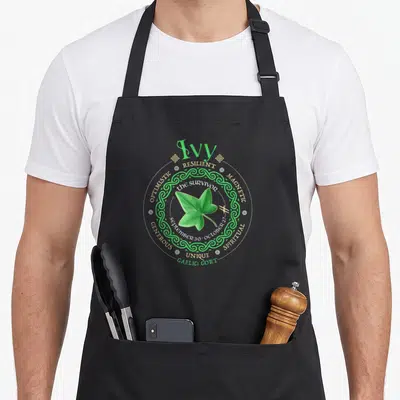 Tablier de cuisine noir avec motif circulaire vert représentant une feuille de lierre et des mots anglais autour.
