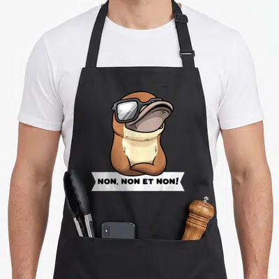 Tablier de cuisine noir avec illustration d'ornithorynque têtu portant des lunettes noires et une bannière textuelle en bas.