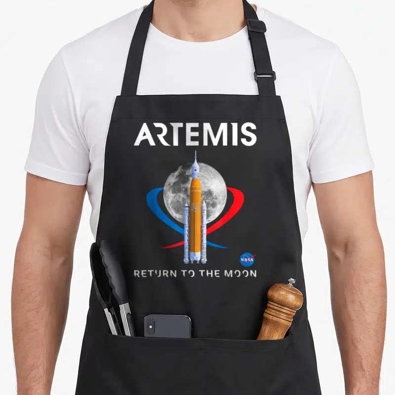 Tablier de cuisine noir avec illustration de la fusée Artemis, de la Lune et du logo NASA.