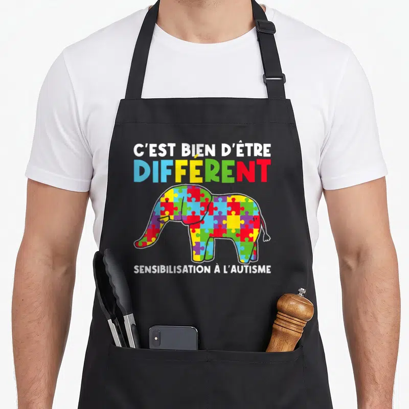 Tablier de cuisine noir avec un éléphant coloré en puzzle et le texte C'est bien d'être différent Sensibilisation à l'autisme.