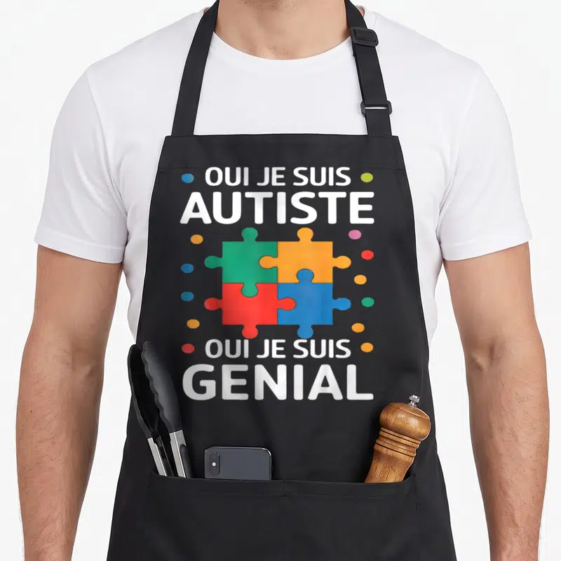 Tablier de cuisine noir avec le texte blanc Oui je suis autiste et génial autour d'un puzzle multicolore.