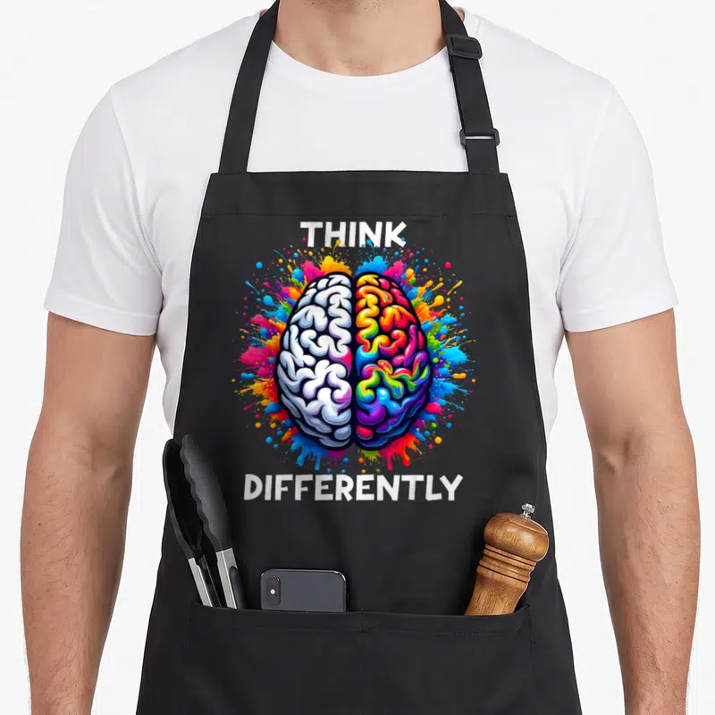 Tablier de cuisine noir avec illustration d'un cerveau bicolore et texte Think Differently en blanc.