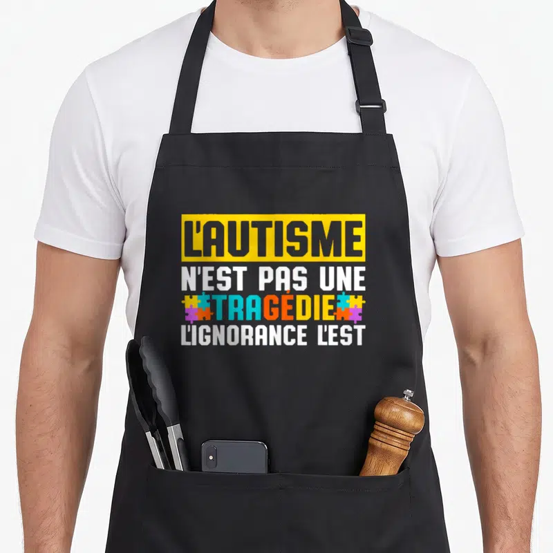 Tablier de cuisine noir avec un message typographique multicolore sur la sensibilisation à l'autisme et des motifs de puzzle.