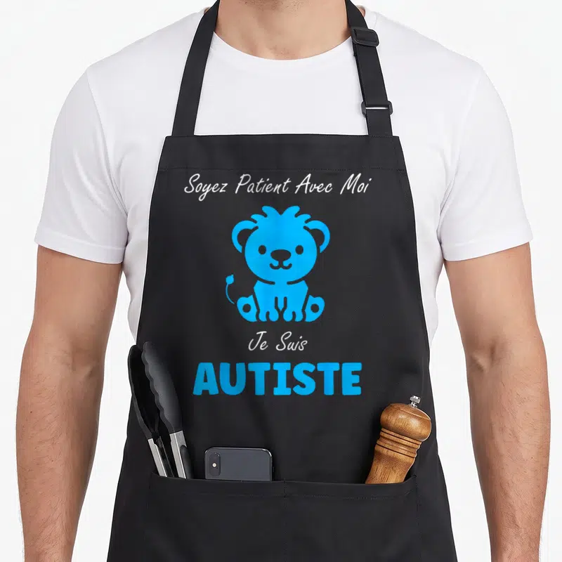 Tablier de cuisine noir avec un lion bleu et le texte Soyez Patient Avec Moi Je Suis AUTISTE imprimé en blanc et bleu.