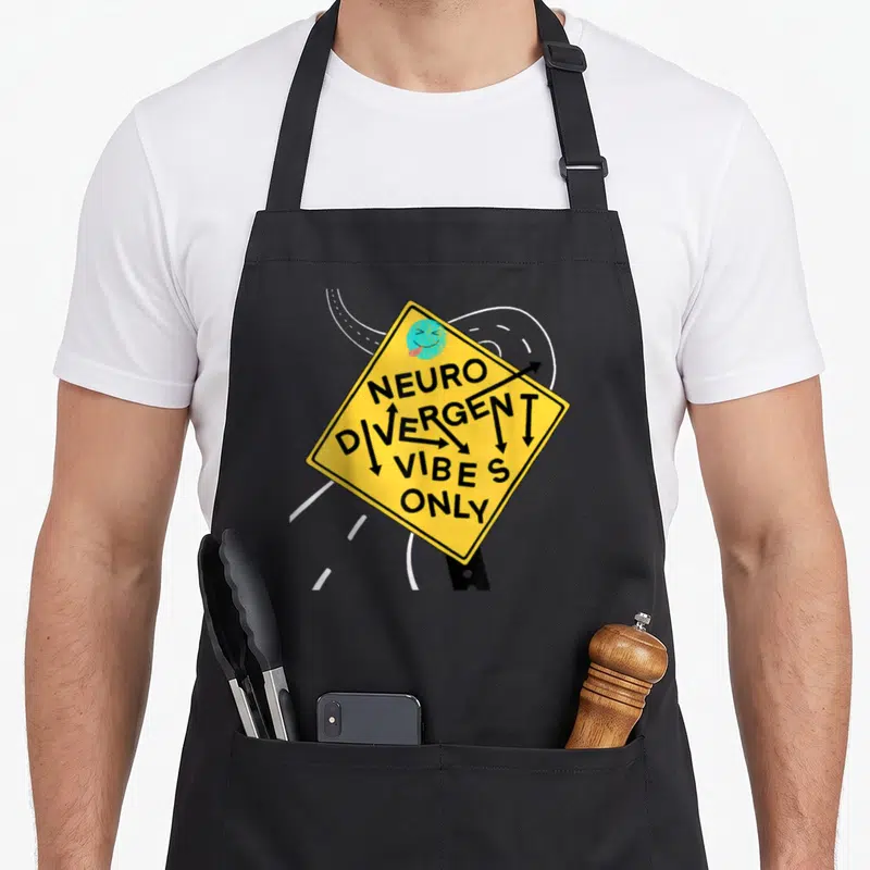 Tablier de cuisine noir avec panneau jaune « Neurodivergent Vibes Only » et flèches noires.