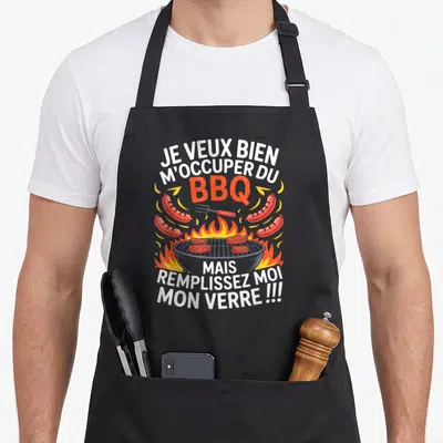 Tablier de cuisine noir avec illustration d'un gril, saucisses, flammes et texte humoristique en blanc et orange.