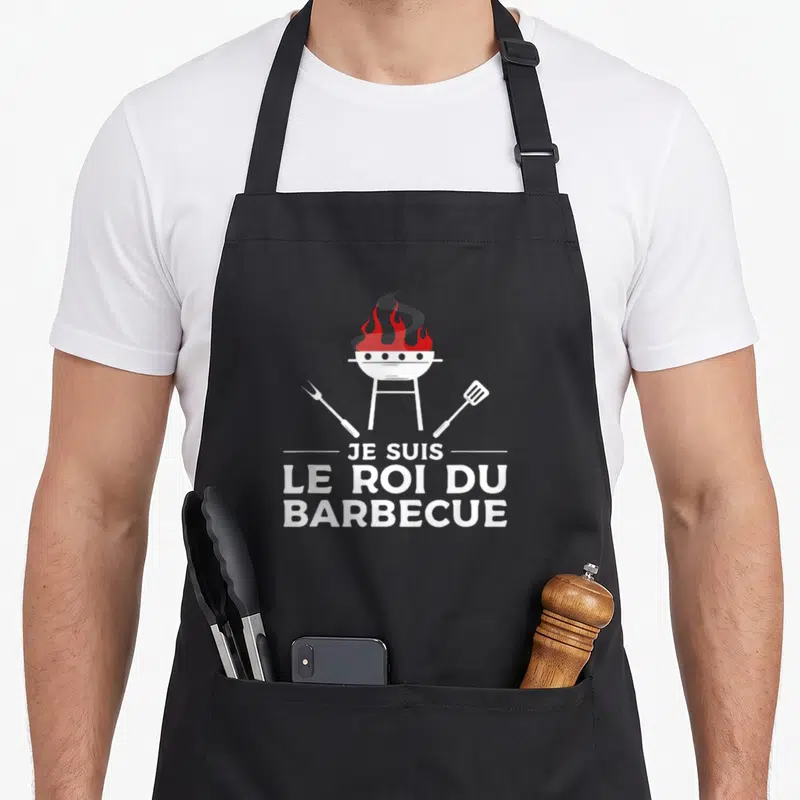 Tablier de cuisine noir avec illustration d'un gril rouge et blanc et le texte Je suis le roi du barbecue.