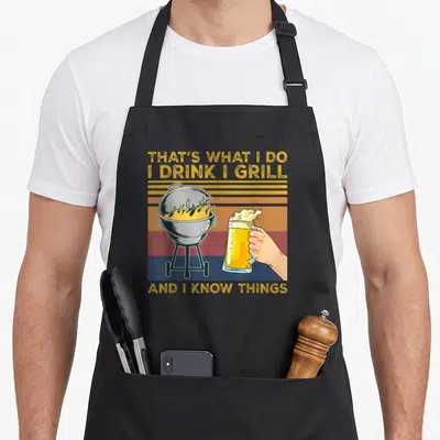 Tablier de cuisine noir avec illustration vintage d'un gril et une main tenant une bière.