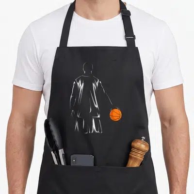 Tablier de cuisine noir avec silhouette blanche d'un basketteur de dos tenant un ballon orange vif.