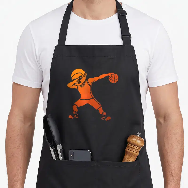 Tablier de cuisine noir avec un joueur de basket-ball orange effectuant une pose de danse.