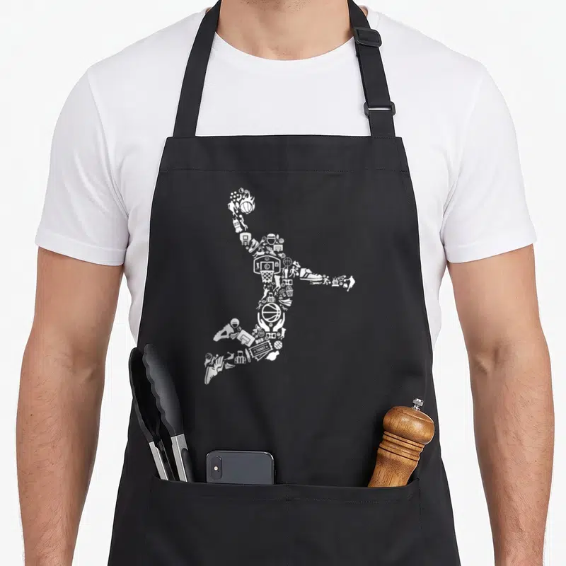 Tablier de cuisine noir avec une silhouette blanche de joueur de basket formée par des icônes sportives et un panier.