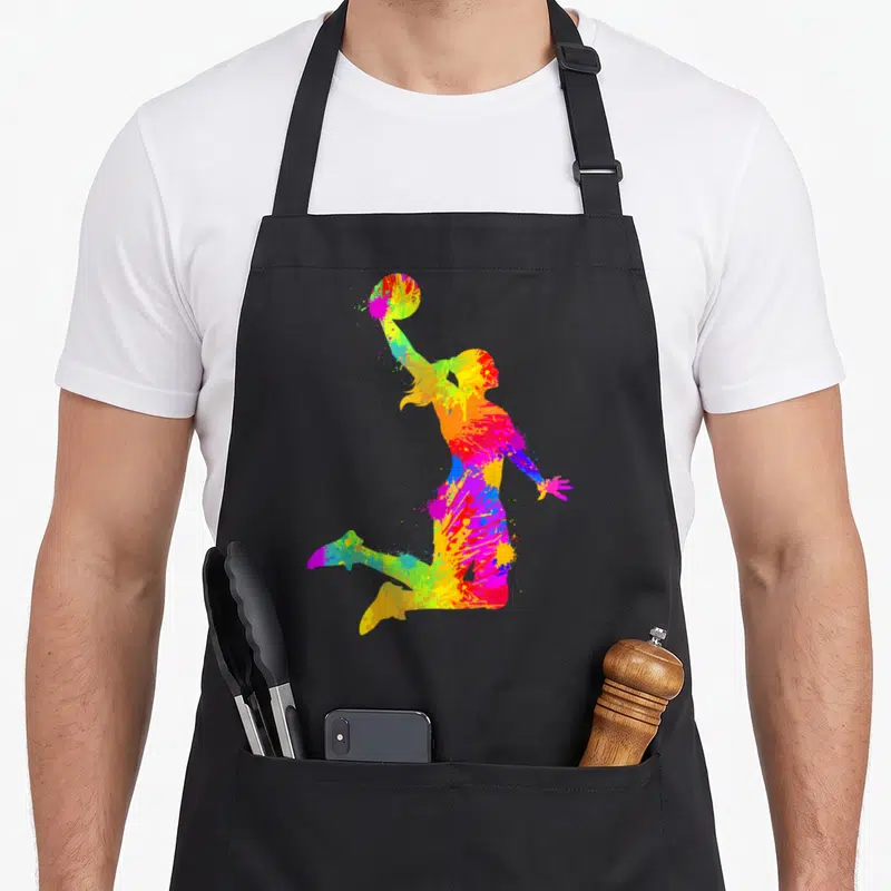 Tablier de cuisine noir avec silhouette femme basketball colorée en éclaboussures artistiques multicolores.