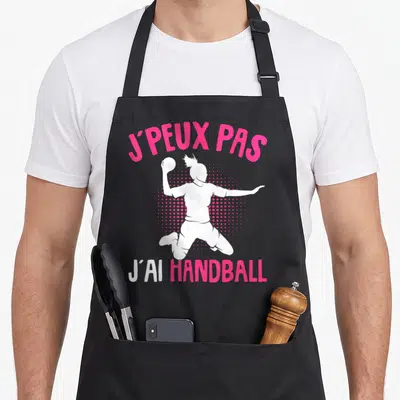 Tablier de cuisine noir avec silhouette handballeuse et texte J'peux pas j'ai handball en rose et blanc.