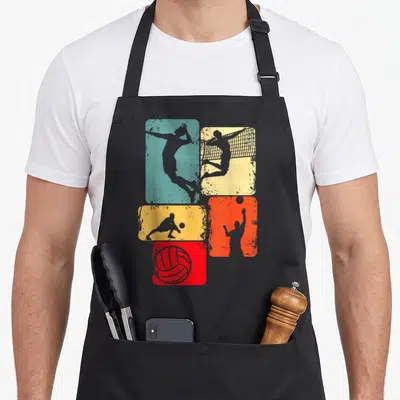 Tablier de cuisine noir avec cinq rectangles colorés affichant des silhouettes de joueurs de volley-ball en action et un ballon rouge.