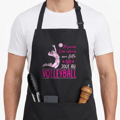 Tablier de cuisine noir avec illustration rose d'une femme effectuant un saut de volley et texte motivationnel imprimé.