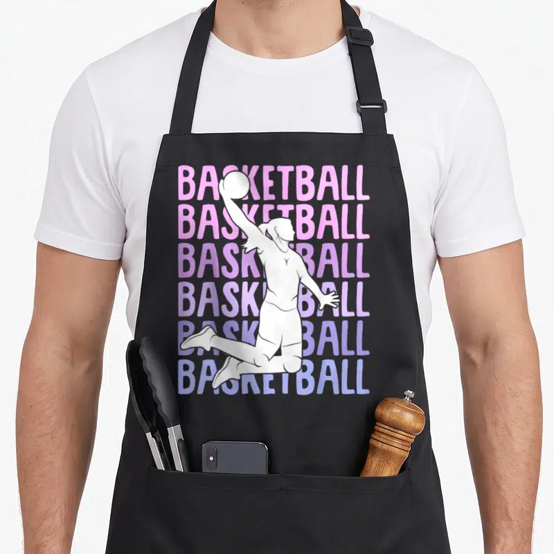 Tablier de cuisine noir avec silhouette blanche de joueuse de basket et texte BASKETBALL en dégradé rose et violet.