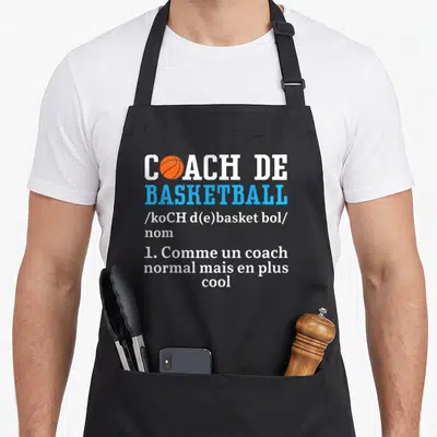 Tablier de cuisine noir avec inscription Coach de Basketball et balle orange stylisée dans le texte blanc et bleu.