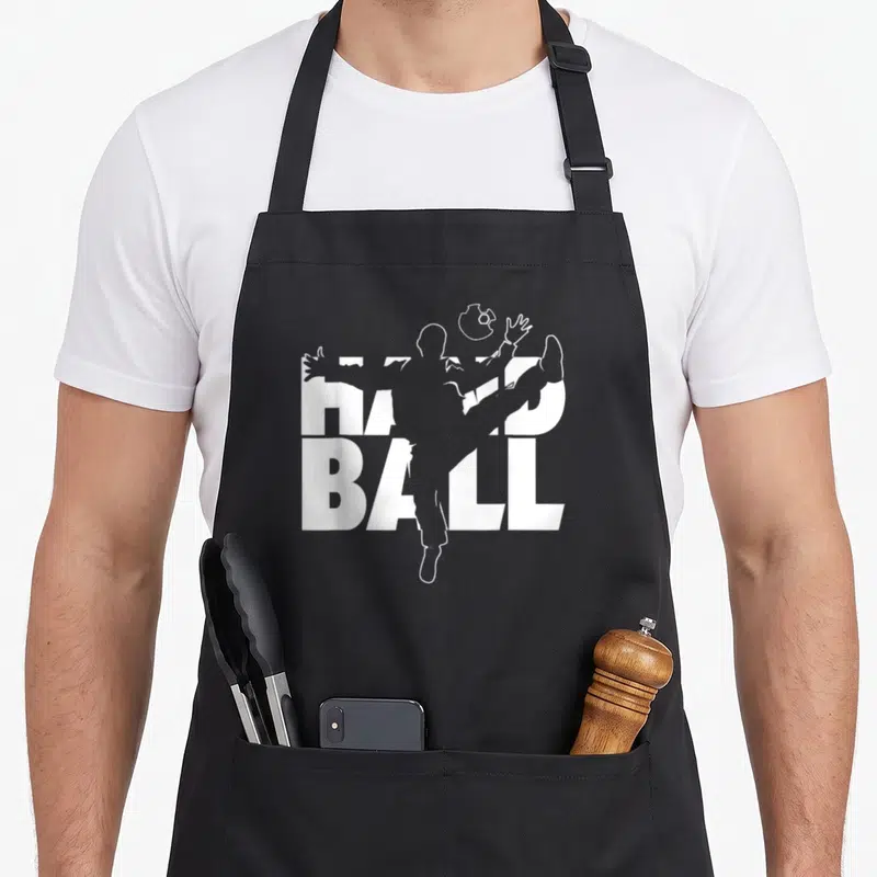 Tablier de cuisine noir avec silhouette blanche d'un gardien de but et le texte HAND BALL en arrière-plan.