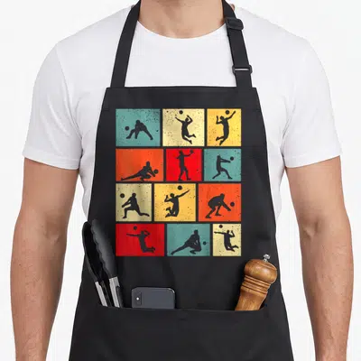 Tablier de cuisine noir avec motifs de silhouettes de joueurs de volley-ball sur fonds colorés quadrillés.