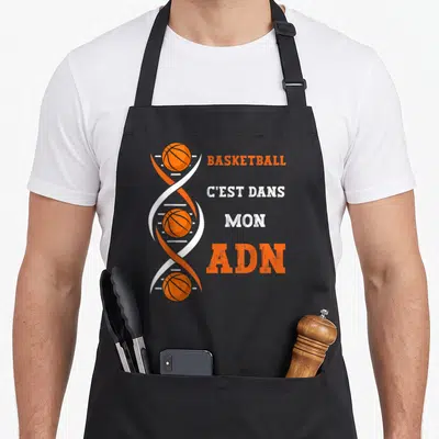 Tablier de cuisine noir avec une double hélice d'ADN contenant des ballons de basket et le texte Basketball c'est dans mon ADN.