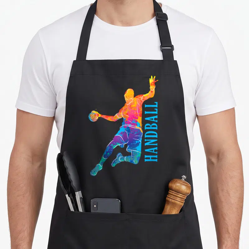 Tablier de cuisine noir avec silhouette colorée d'un joueur de handball et texte vertical bleu HANDBALL.