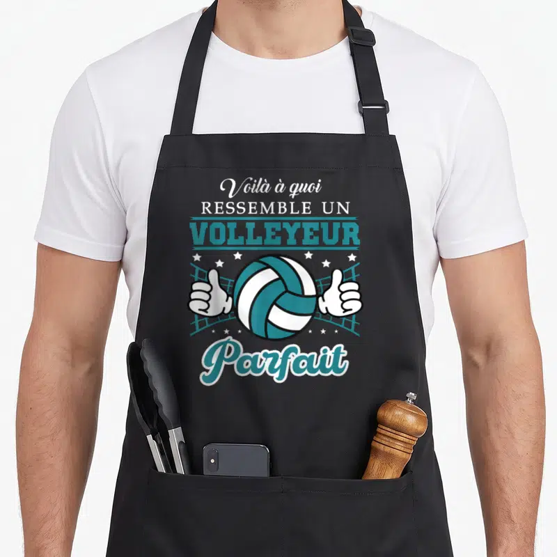 Tablier de cuisine noir avec illustration d'un ballon de volley blanc et turquoise encadré par deux mains faisant un signe d'approbation.