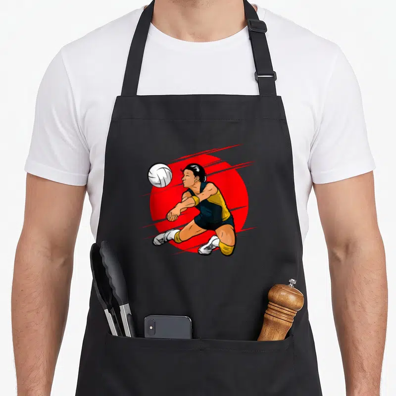 Tablier de cuisine noir avec illustration d'une femme jouant au volley-ball sur fond rouge circulaire.