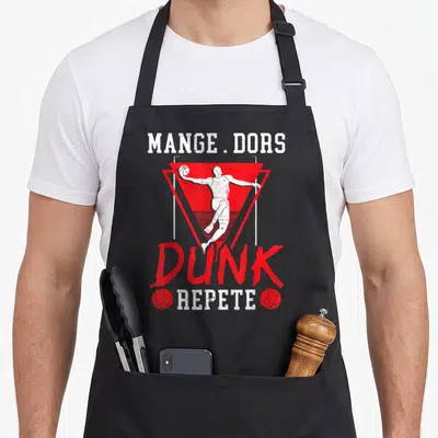 Tablier de cuisine noir avec illustration d'un basketteur et le texte Mange Dors Dunk Repete en rouge et blanc.